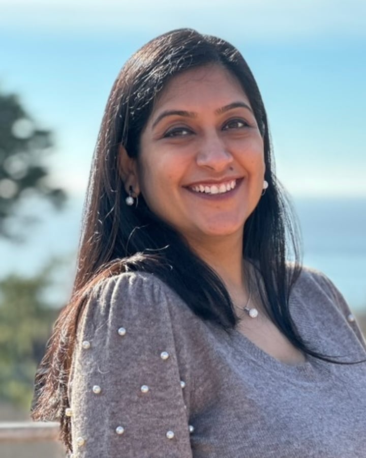 Dr. Ruchi Masand, smiling, on a balcony with the ocean behind her